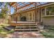 Inviting backyard deck with wooden pergola, string lights, grill, and steps leading to a flagstone patio and grassy lawn at 29551 Dorothy Rd, Evergreen, CO 80439