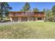 Two-story home with brick facade, a two-car garage, upper deck with wood railing, and mature trees at 29551 Dorothy Rd, Evergreen, CO 80439