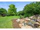 Landscaped backyard featuring a rock water feature surrounded by lush greenery and an expansive lawn at 6364 S Walden Ct, Aurora, CO 80016