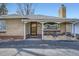 Charming front porch detail on a brick home with a cozy sitting area and beautiful plants at 4585 Garrison St, Wheat Ridge, CO 80033