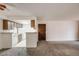 Open-concept space featuring neutral walls, carpet, a door, and a glimpse into the connected kitchen area at 14192 E Colorado Dr # 102, Aurora, CO 80012