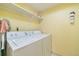 Well-lit laundry room with washer, dryer, and overhead shelf for organized storage solutions at 6001 S Yosemite St # B203, Greenwood Village, CO 80111