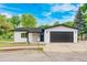 Charming one-story home featuring a stucco exterior, stone accents, and a black attached two-car garage at 6882 Quail St, Arvada, CO 80004
