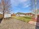 Well-maintained backyard featuring a shed, stone ground cover, green grass, and wood fence at 206 River Rd, Platteville, CO 80651
