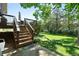 A view of the backyard, deck stairs, green grass, and lush green foliage at 5616 S Kenton Ct, Englewood, CO 80111
