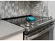 Close up of the stove top with stainless steel hardware and gray quartz countertops at 6600 E Mississippi Ave # 7, Denver, CO 80224
