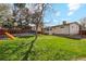 Expansive backyard featuring a large green lawn, mature trees, and a play set for outdoor enjoyment at 320 Orion St, Golden, CO 80401