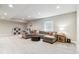 Cozy carpeted basement featuring a large sectional sofa, perfect for relaxation and entertainment at 7240 S White Crow Way, Aurora, CO 80016