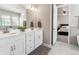 Bright bathroom featuring double vanity, quartz countertops, white cabinetry and a glimpse into the carpeted bedroom at 7240 S White Crow Way, Aurora, CO 80016
