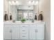 Bright bathroom featuring double sinks, storage, and large mirror at 7240 S White Crow Way, Aurora, CO 80016