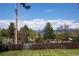 Expansive backyard with lush green lawn, mature trees, and scenic mountain views beyond the wooden fence at 4667 Ashfield Dr, Boulder, CO 80301