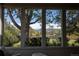 Sunroom view through large windows, showcasing lush backyard trees and glimpses of distant mountains at 4667 Ashfield Dr, Boulder, CO 80301