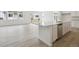 Bright kitchen with a large island, stainless steel dishwasher, and wood floors leading to the living space at 45915 Wood Thrush Ave, Bennett, CO 80102