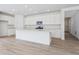 Open kitchen features an island, white cabinets, stainless steel microwave, and bright lighting at 45915 Wood Thrush Ave, Bennett, CO 80102