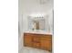 Bathroom with wood vanity, a white countertop, and an illuminated mirror over a sink with shower in the mirror reflection at 3341 S Monaco Pkwy # A, Denver, CO 80222