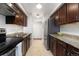 Galley kitchen features stainless appliances, tile backsplash, and dark wood cabinets at 3341 S Monaco Pkwy # A, Denver, CO 80222