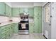 The updated kitchen boasts bright green cabinets, stainless steel appliances, and new backsplash at 1332 Ash St, Denver, CO 80220