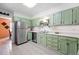 Bright kitchen with stainless steel appliances, tiled floors, and light green cabinetry at 1332 Ash St, Denver, CO 80220