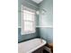 Bathroom with a clawfoot tub, rain shower head, and decorative privacy window at 4430 Zuni St, Denver, CO 80211