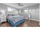 A primary bedroom features hardwood floors, a ceiling fan, light gray walls, and abundant natural light from large windows at 482 W Caley Ave, Littleton, CO 80120