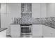 Modern kitchen features white cabinets, stainless steel appliances, and gray diamond patterned backsplash at 482 W Caley Ave, Littleton, CO 80120