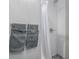 Close-up of bathroom shower with tiled walls and gray towels hanging on the wall at 482 W Caley Ave, Littleton, CO 80120