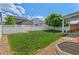 Spacious backyard with a well-maintained lawn, a covered patio area, and a white fence at 4670 Tanner Peak Trl, Brighton, CO 80601