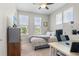 Bright bedroom featuring carpet, a ceiling fan, three windows, and an office space with a desk at 4670 Tanner Peak Trl, Brighton, CO 80601