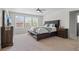 Spacious primary bedroom with large windows, ceiling fan, neutral carpeting, and stylish furnishings at 4670 Tanner Peak Trl, Brighton, CO 80601