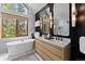 Elegant bathroom featuring a soaking tub, a double sink vanity, and stylish lighting fixtures at 110 Windwood Cir, Breckenridge, CO 80424