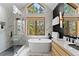 Luxurious bathroom with a soaking tub, a glass shower, and bright windows overlooking a wooded area at 110 Windwood Cir, Breckenridge, CO 80424