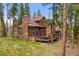 Stunning multi-story home featuring a stone chimney, wooden siding, large windows and a wraparound deck at 110 Windwood Cir, Breckenridge, CO 80424