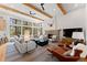 Spacious living room with beamed ceilings, large windows, stone fireplace, and comfortable seating at 110 Windwood Cir, Breckenridge, CO 80424