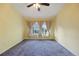 A yellow-walled bedroom with a ceiling fan and a view from the window at 3857 Mossy Rock Dr # 201, Highlands Ranch, CO 80126