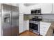 Bright kitchen with stainless steel fridge, range, oven, and granite countertops, complemented by white cabinetry at 3857 Mossy Rock Dr # 201, Highlands Ranch, CO 80126