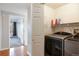 Laundry room includes modern washer and dryer units, a shelf for supplies, and easy access to the bedroom at 3857 Mossy Rock Dr # 201, Highlands Ranch, CO 80126