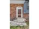 Classic front entrance with decorative doorframe, brick facade, and manicured landscaping at 11506 Fowler Dr, Northglenn, CO 80233