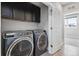 Convenient laundry room with modern washer and dryer and black cabinets above at 815 Promenade Dr, Superior, CO 80027