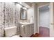 Well-lit bathroom with a modern vanity, decorative mirror, stylish wallpaper, and a toilet at 2990 E 135Th Dr, Thornton, CO 80241