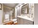 Stylish bathroom with a glass-enclosed shower, modern vanity, decorative mirror, and unique wallpaper at 2990 E 135Th Dr, Thornton, CO 80241