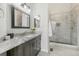 This renovated bathroom has a granite-topped vanity, a glass-enclosed shower with modern fixtures, and neutral tile at 4929 W 73Rd Ave, Westminster, CO 80030