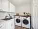 Convenient laundry room equipped with a sink, storage cabinets, and modern washer and dryer at 4 Mountain Ash, Littleton, CO 80127