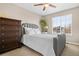 Comfortable bedroom with soft gray bed, dresser, and window providing warm natural light at 16525 Sanford St, Mead, CO 80542