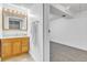 Bathroom with wood cabinet, light countertop, wall mirror, doorway into finished basement area with carpet at 8705 W 86Th Dr, Arvada, CO 80005