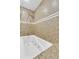 Bathroom with white tub, brown tiled walls with a white stripe and shower head at 8705 W 86Th Dr, Arvada, CO 80005
