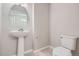 A well-lit bathroom featuring a pedestal sink, a round mirror and modern fixtures at 9269 Garnett St # C, Arvada, CO 80007