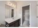 Bright bathroom featuring dark wood vanity with white countertop, framed mirror, and access to a walk-in closet at 9269 Garnett St # C, Arvada, CO 80007