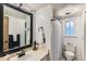 Well-lit bathroom featuring vanity with large framed mirror and shower-tub combo with white shower curtain at 12556 Elm St, Thornton, CO 80241