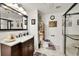 Well-lit bathroom with a dark wood vanity, decorative mirror, and a shower with a glass door at 13124 Ivy Pl, Thornton, CO 80602