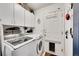 Laundry room with modern washer and dryer, storage cabinets, and a pet door at 13124 Ivy Pl, Thornton, CO 80602